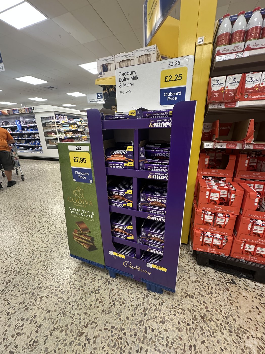 A real Cadbury Dairy Milk & More quarter-pallet display next to a Godiva promotional unit in a Tesco store aisle