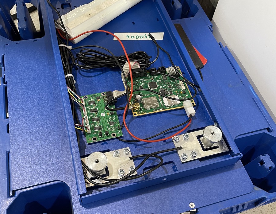 Underside of a quarter-pallet display showing an early weight-sensor hardware prototype wired into the base