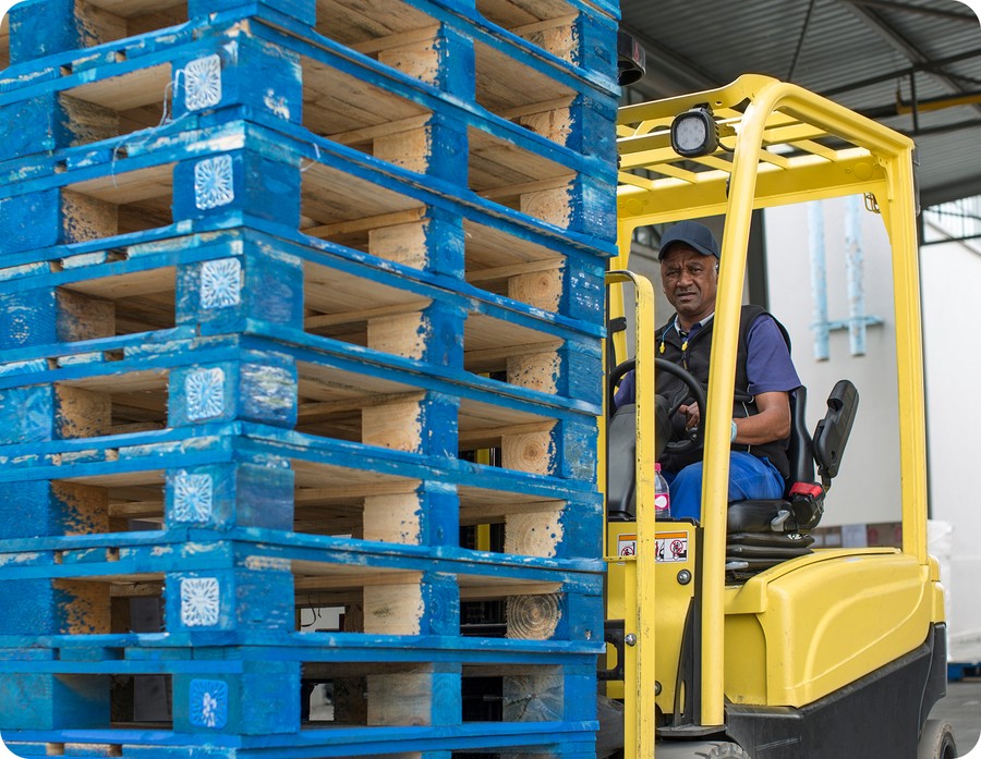 Standard full-size pallets fitted with an ultra-wideband location device being moved by forklift in a warehouse