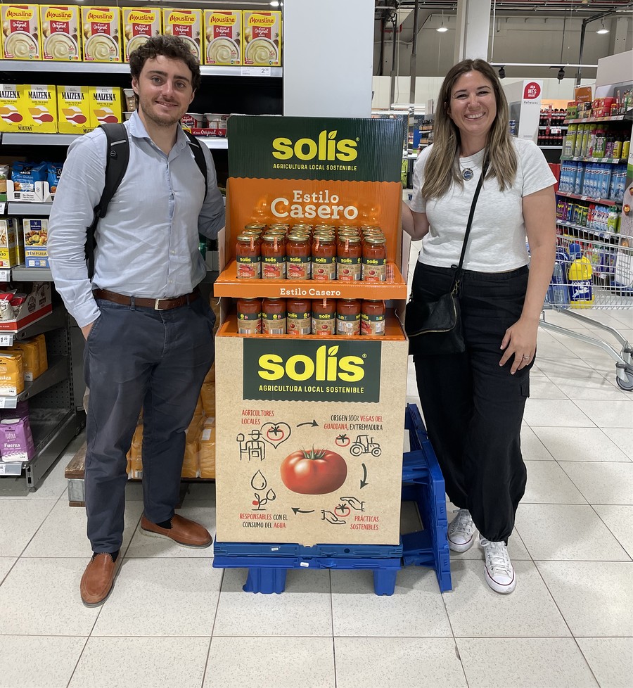 Two people standing beside a Solis-branded quarter-pallet promotional display inside a Spanish retail store